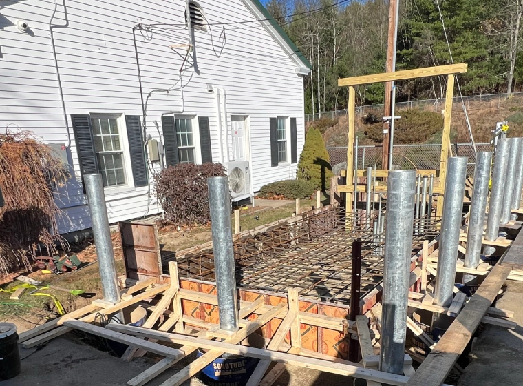 concrete base and structure base with a white house at the left side and trees at the back